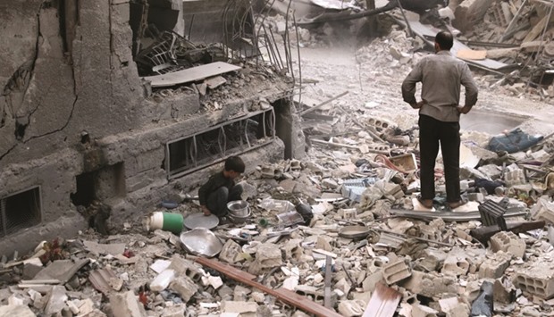A Syrian boy collecting items amidst the rubble of destroyed buildings yesterday, following  air strikes in the rebel-held town of Douma, on the eastern outskirts of the capital Damascus. More than a dozen raids and several mortar rounds pounded Douma, said the Syrian Observatory for Human Rights monitoring group.