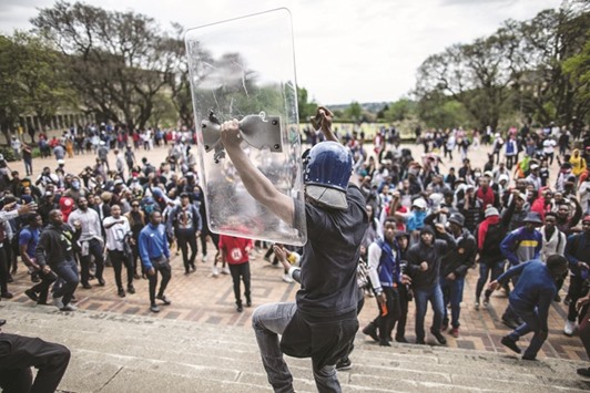 Mcebo Dlamini, the leader of the University of Witwatersrand students, dances with a helmet belonging to the universityu2019s private security and with a shield during a running battle with police forces on campus as he takes part in a mass demonstration yesterday in Johannesburg.