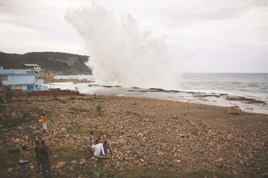 People watch waves splashing on the beach at Siboney ahead of the arrival of Hurricane  Matthew in Cuba.