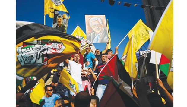 Palestinians supporting the Fatah movement wave both their national and the movementu2019s flags as they take part in a demonstration in the West Bank city of Ramallah yesterday in support of President Mahmoud Abbasu2019 participation in the funeral ceremony of former Israeli President Shimon Peres earlier in the week.