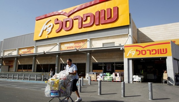 A man pushes a shopping cart outside Shufersal, Israel's largest supermarket chain, in the West Bank Jewish settlement of Mishor Adumim near Jerusalem.