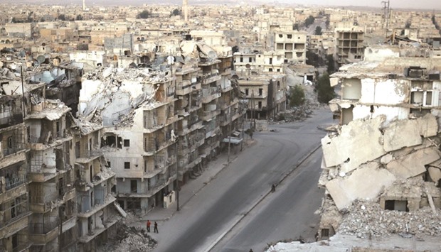 People walk past damaged buildings in the rebel-held Tariq al-Bab neighbourhood of Aleppo, Syria, yesterday.