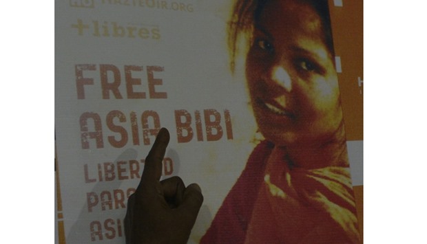 Ashiq Masih, husband of Asia Bibi, a Christian woman facing death sentence for blasphemy, points to a poster bearing an image of his wife Asia at a living area in Lahore.