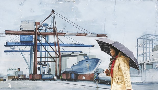 A woman walks past a painting at Keelung port. Taiwanu2019s exports, which increased the two previous months, in September contracted 1.8% from a year earlier, the finance ministry said yesterday.
