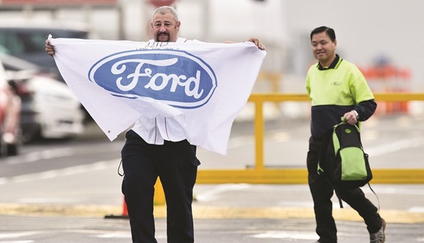 A worker at the Ford Motoru2019s Broadmeadows Assembly Plant holds a flag as he leaves the factory with a fellow worker before it closes in the Melbourne suburb of Campbellfield, Australia, yesterday.
