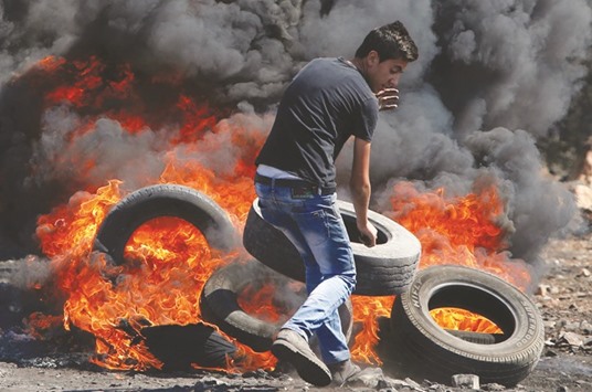 A Palestinian protester burns tyres during clashes with Israeli security forces following a weekly demonstration against the expropriation of Palestinian land by Israel in the village of Kfar Qaddum, near Nablus in the occupied West Bank yesterday.