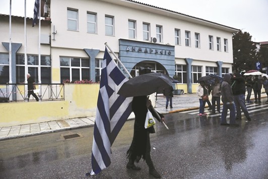 A woman holds the Greek national flag as she heads to a gathering in Oreokastro, a suburb north of Thessaloniki, on Friday. The Parents and Guardians Association of the 5th Primary School of Oreokastro last month have warned that they will occupy the school grounds if migrant children are inducted in the school.