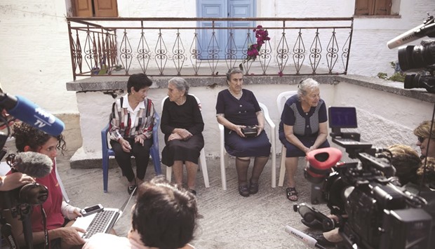 Emilia Kamvysi (second right) and her friends are surrounded by journalists at the Skala Sikamias village on the island of Lesbos during the announcement on Friday of the Nobel Peace Prize winner.