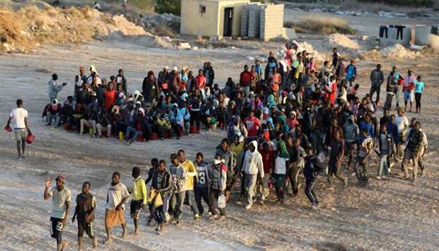 Migrants wait to receive food at a detention center in the coastal city of Sabratha, Libya