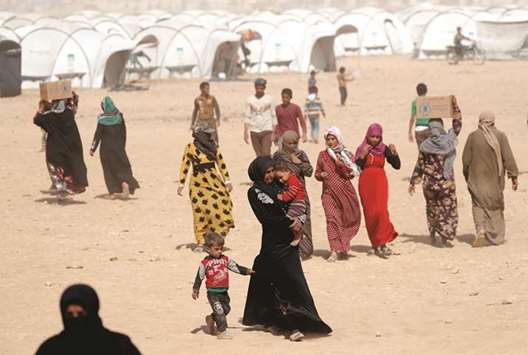 People displaced from fightings between the Syrian Democratic Forces and Islamic State militants carry boxes of food aid given by UNu2019s World Food Programme at a refugee camp in Ain Issa, yesterday.