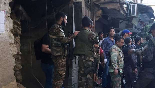 Syrian Army soldiers inspect the damaged site at the police HQ in central Damascus