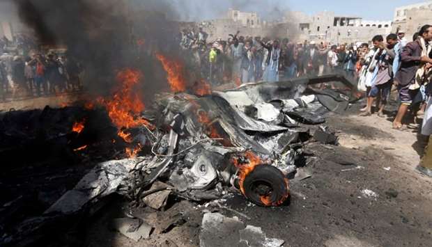 Yemenis gather around burning wreckage of a drone in the country's capital Sanaa