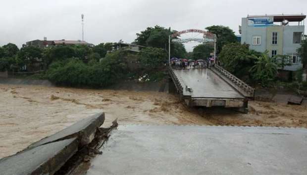Residents standing at an end of a destroyed bridge in the northern province of Yen Bai