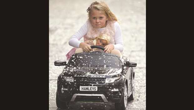 Six-year-old Lillie poses with a childrenu2019s Range Rover Evoque ride-on car and a Barbie fashion doll, which form part of the selection of predicted top sellers this Christmas at the Hamleys toy store in London yesterday.