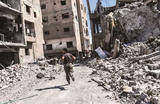 A member of the Syrian Democratic Forces (SDF) runs as they take position near the central hospital of Raqqa yesterday.