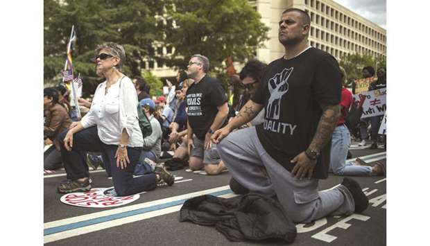 Protesters take a knee near the Trump Hotel as they take part in the march for racial justice in Washington, DC.