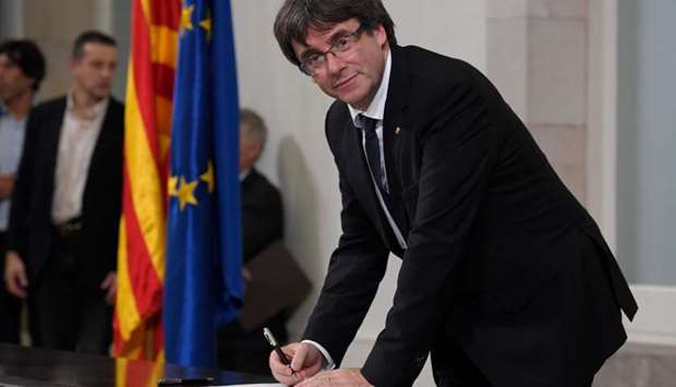 Catalan regional government president Carles Puigdemont signs a document about the independence of Catalonia at the Catalan regional parliament in Barcelona on October 10, 2017.