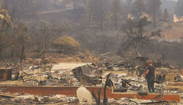 A woman surveys the remains of a home destroyed by wildfire in Napa, California.