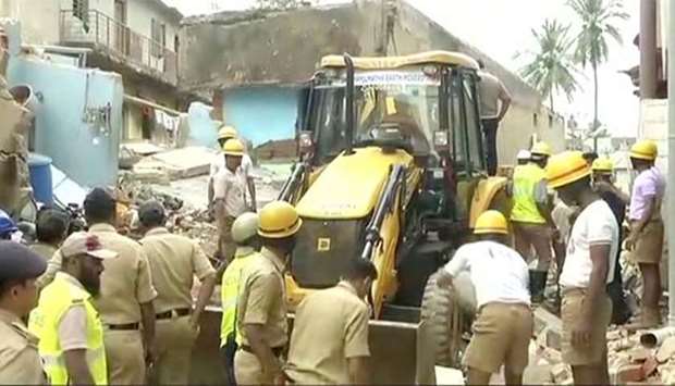 Rescue workers and police are seen next to an excavator following a building collapse in Bengaluru on Monday.