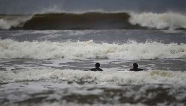 Surfers watch as waves approach in the Atlantic on the eve of Hurricane Ophelia, in Lahinch, Ireland on Sunday.