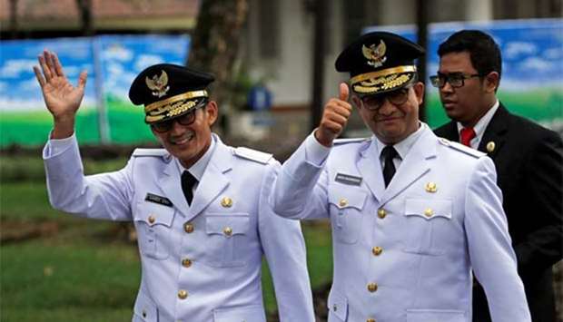 Jakarta Governor Anies Baswedan (right) and his deputy Sandiaga Uno wave to reporters before a swearing-in at the Presidential Palace in Jakarta on Monday.