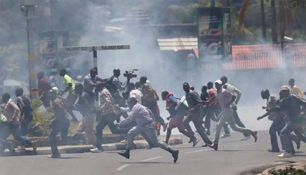 Supporters of Kenyan opposition National Super Alliance coalition run as riot policemen fire tear gas to disperse them during a protest along a street in Nairobi