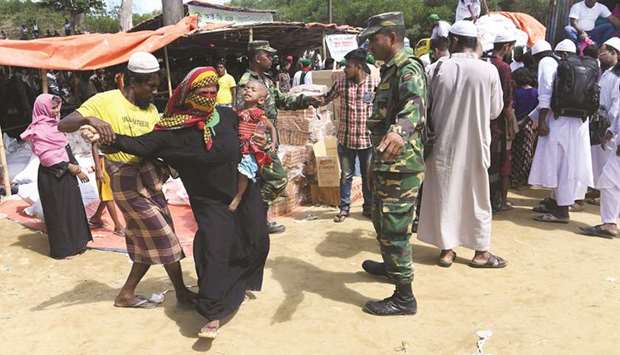 A volunteer pulls out a Rohingya refugee from a queue to collect aid after she came back a second time at the Balukhali refugee camp in the Bangladeshi district of Ukhia.