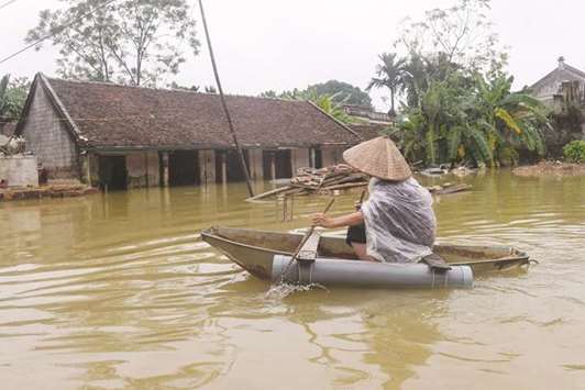 A villager paddles on a small boat past flooded houses at Tat Dong village in Hanoiu2019s outskirt district of Chuong My yesterday.
