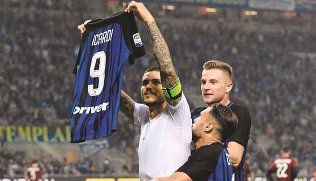 Inter Milanu2019s captain Mauro Icardi shows his jersey to supporters as he celebrates with teammates after winning the Serie A match against AC Milan at the San Siro Stadium in Milan on Sunday night. (AFP)