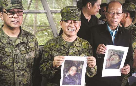 Military chief General Eduardo Ano (centre) holds an image of militant leader Isnilon Hapilon, next to Defence Secretary Delfin Lorenzana (right) showing an image of Omarkhayam Maute, and Western Mindanao Commanding General Carlito Galvez  during a press conference at a military camp in Marawi on the southern island of Mindanao yesterday.