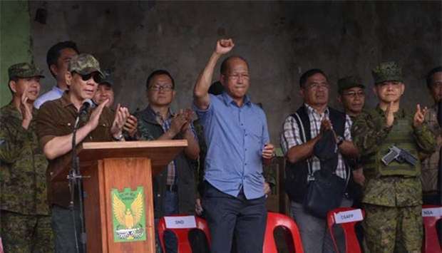 President Rodrigo Duterte (front left) applauds as he declares Marawi city ,liberated, during a ceremony inside the battle area in Marawi on Tuesday, as Defence Secretary Delfin Lorenzana (in blue) raises a clenched fist.