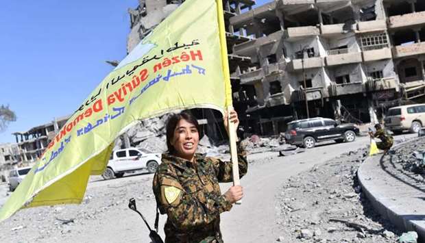 Rojda Felat, a Syrian Democratic Forces (SDF) commander, waves her group's flag at the iconic Al-Naim square in Raqqa.