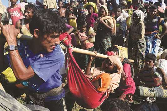 Rohingya refugees carry a woman after crossing the Naf River as they flee violence in Myanmar to reach Bangladesh in Palongkhali near Ukhia on Monday.