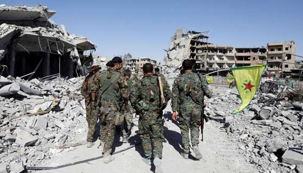 Fighters of Syrian Democratic Forces walk past the ruins of destroyed buildings near the National Hospital after Raqqa was liberated from the Islamic State militants, in Raqqa, Syria. Reuters
