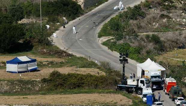 Forensic experts and police conduct their investigation two days after a powerful bomb blew up a car (L under blue and white tent) and killed investigative journalist Daphne Caruana Galizia in Bidnija, Malta