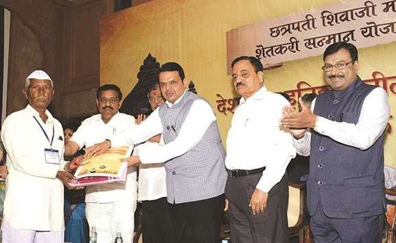 Maharashtra Chief Minister Devendra Fadnavis hands over documents to a farmer as part of the loan waiver scheme in Mumbai yesterday.