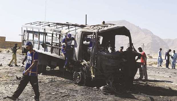 Pakistani investigators collect evidence from a burnt police truck after a suicide blast on the outskirts of Quetta yesterday.