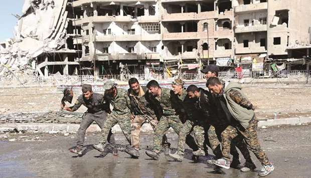 Fighters of Syrian Democratic Forces dance along a street in Raqqa, yesterday.