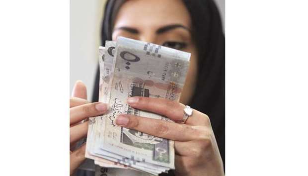 A Saudi woman counts Saudi riyal banknotes at a money exchange shop in Riyadh. The growth slump is a threat to ambitious economic reforms announced by Crown Prince Mohammed bin Salman.