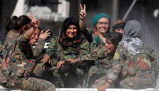 Female fighters of Syrian Democratic Forces gesture the ,V, sign while onboard a pickup truck in Raqqa.
