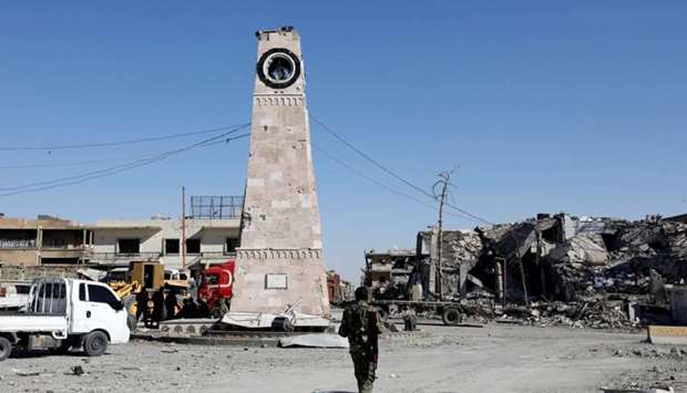 A fighter of Syrian Democratic Forces walks towards a clock tower in Raqqa, Syria.