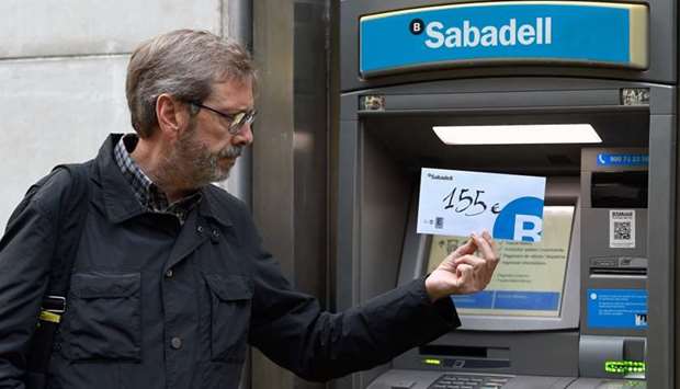 Joaquim Curbet poses with an envelope with 155 euros inside after withdrawing that amount of money from a Banc Sabadell ATM during a protest called by the Catalan National Assembly (ANC) and Omnium Cultural to show their dissatisfaction with the Spanish government in Barcelona.