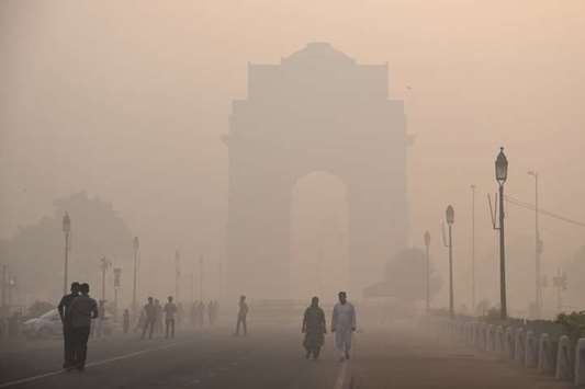Pedestrians walk near the India Gate monument amid heavy smog in New Delhi yesterday.