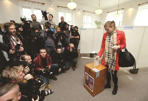 A woman casts her vote in parliamentary elections, as members of the media wait for Babis, at a polling station in Prague.