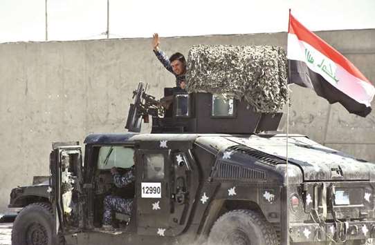 A fighter loyal to the federal goverment waves from a humvee carrying the Iraqi national flag on a road in the region of Altun Kupri, about 50 kilometres from Erbil.