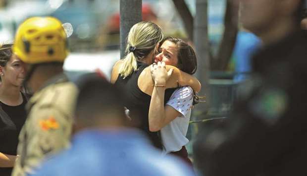 A woman comforts a young girl at the scene of a shooting at the Goyases private school in Goiania, Goias, yesterday.