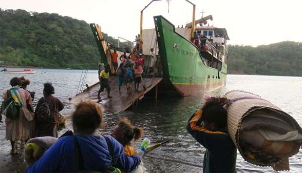 Residents carrying their possessions board a boat at Lolowai Port as they evacuate due to the Manaro Voui volcano