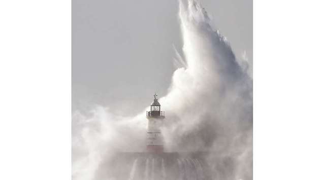 Waves crash over Newhaven Lighthouse on the south coast of England yesterday as Storm Brian hits the country.