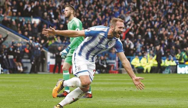 Huddersfield Townu2019s Laurent Depoitre celebrates scoring a goal as a dejected Manchester United goalkeeper David De Gea walks by during their English Premier League match in Huddersfield, England, yesterday. (Reuters)