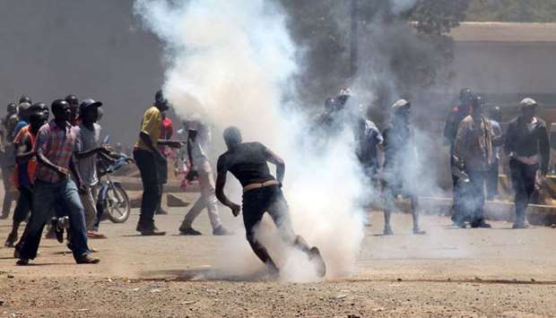 Protesters react to tear gas fired by riot policemen during a protest by opposition supporters against the retention of the election officials they blame for August's botched elections, in Kisumu, Kenya.